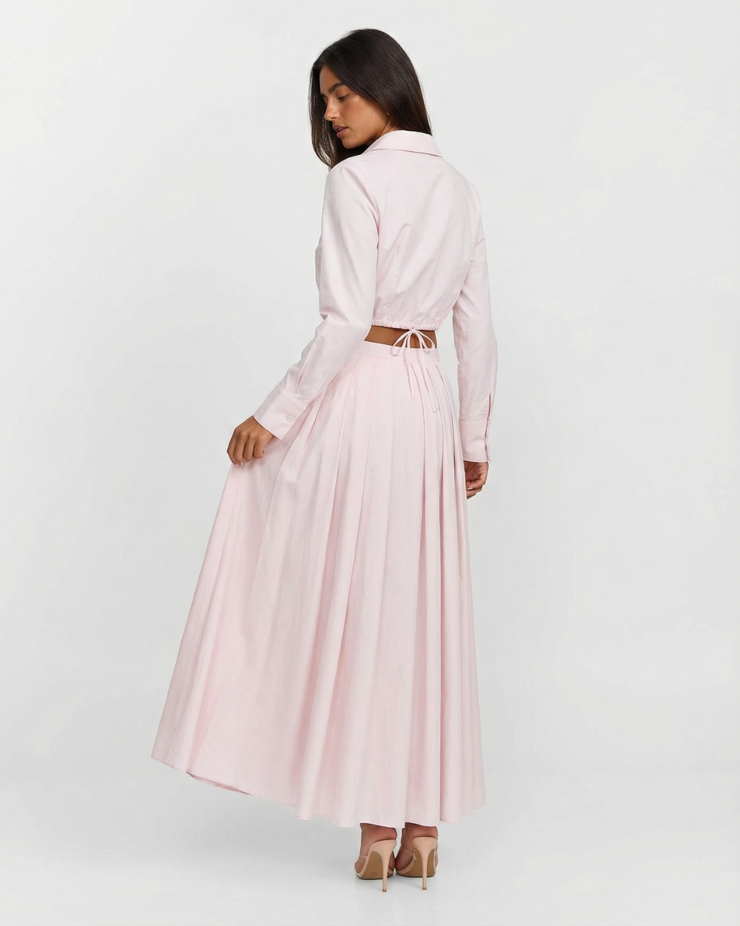 Woman wearing a light pink dress with a belt on a white background