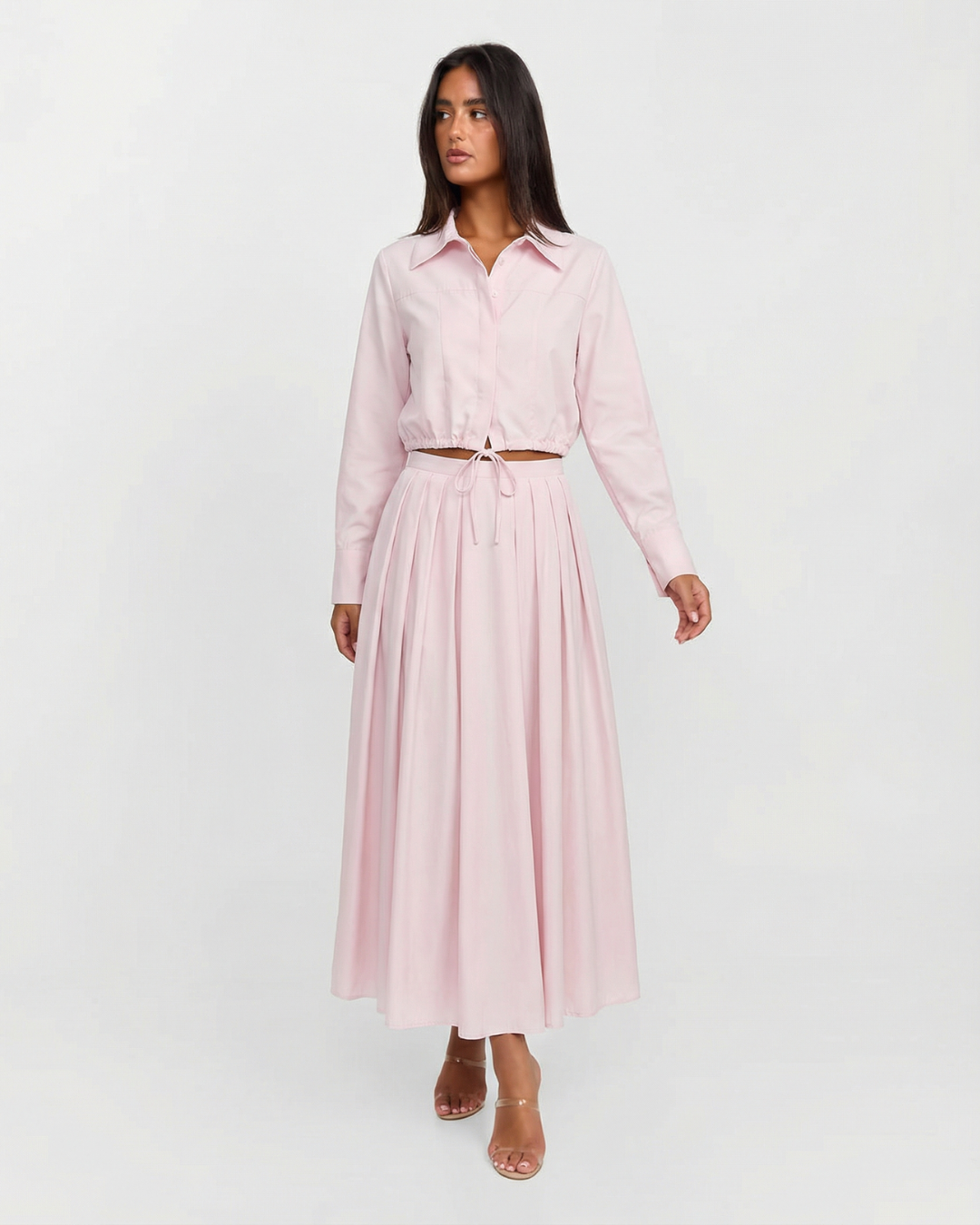 Woman wearing a light pink dress with a belt on a white background